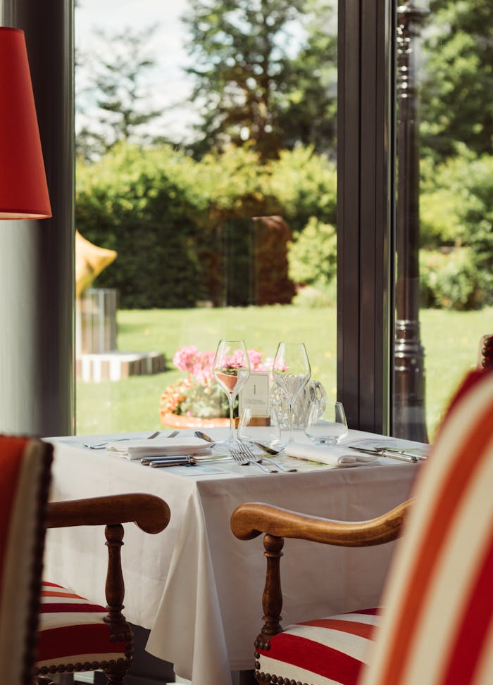 Contact Luxury dining setup at a French restaurant overlooking a lush garden in Vonnas, France.